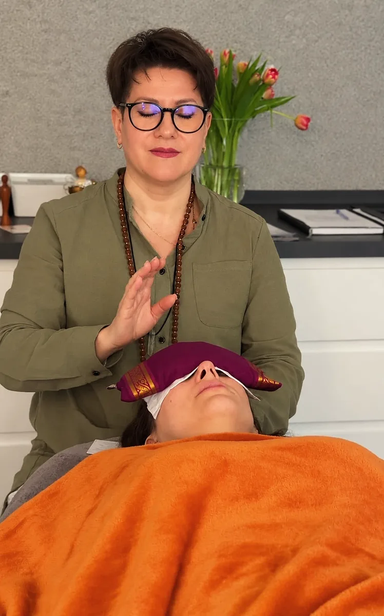 Elena Dieterle bei einer Heilenergiebehandlung, die Klientin liegt mit Augenkissen unter einer Decke